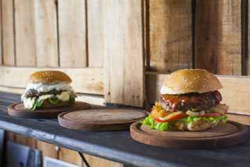 Three tasty different hamburgers on a wooden table.