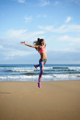 Sporty brazylijska kobieta tańczy i skacze na plaży. Czarny szczęśliwy tancerz ćwiczy taniec skacze i ma zabawę plenerową. - 122786127