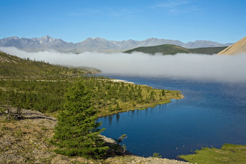 Naklejka na ściany i meble A cloud of mist over a mountain lake. Lake Darpir. Yakutia. Russia.