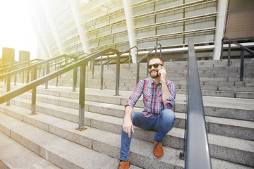 Happy young bearded man talking on the mobile phone and smiling