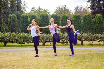 Obraz premium The group of three beautiful young women doing sport in sunny day in the park. happiness and health care sport outdoors.