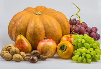 Still life, autumn food on white background - Pumpkin, chestnuts, walnuts, persimmon, peer, apple, pomegranate, grapes