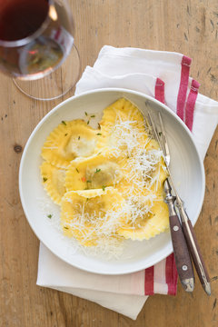 Butter and thyme ravioli served with grated parmesan cheese and glass of red wine