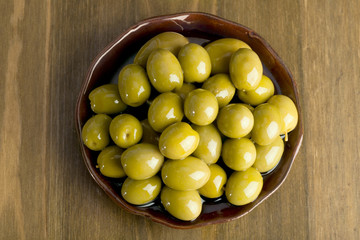 green olives in oil stacked on a ceramic plate