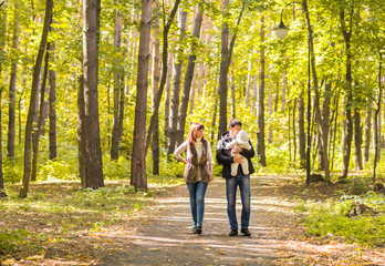 Fototapeta premium Happy young family walking down the road outside in autumn nature.