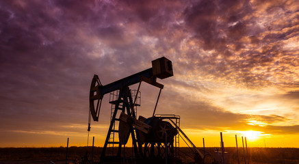 Naklejka premium Oil and gas well profiled on dramatic sunset sky, with wild colors, in a remote oil field in Eastern Europe