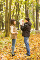 Portrait of happy young couple with baby son in autumn park