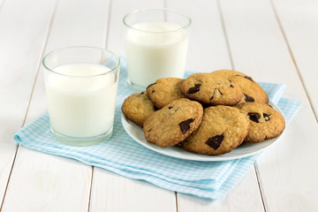 Homemade cookies with chocolate pieces and milk on the table.