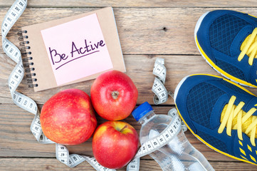 Sport shoes, red apples, bottle of water, measuring tape and words 