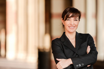 Confident lawyer businesswoman professor with arms crossed on university college campus with columns in background