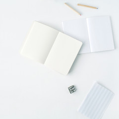 clean blank sketchbook, pencils and pencil sharpener on white background. flat lay, top view