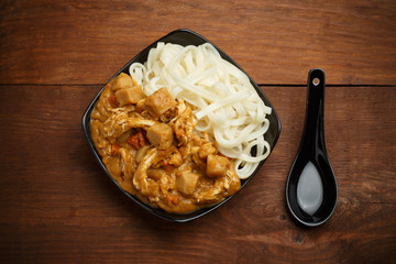 Curry sauce and noodles in blackplate at wooden table