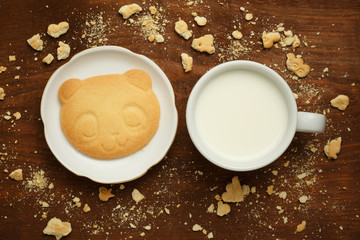 Bear cookie, milk and crumbs at wooden table