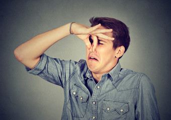 man pinches nose looks with disgust something stinks bad smell