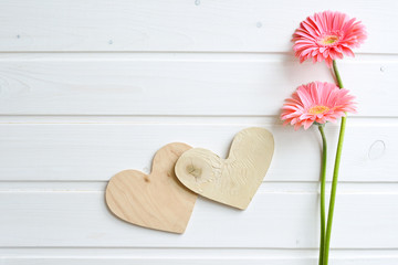 Two pink gerber daisy flowers on  wooden backgraund. Gerbera and decorative heart. Flat lay, top view