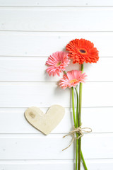 Pink gerber daisy flowers on  wooden backgraund. Gerbera and decorative heart. Flat lay, top view