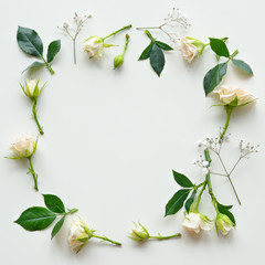 Assorted roses heads on white background. Flowers and leaves scattered on a table, overhead view wallpaper. Flat lay, top view. Nice border.