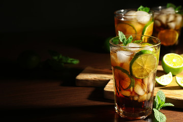 Cuba libre cocktails with lime and mint on wooden table