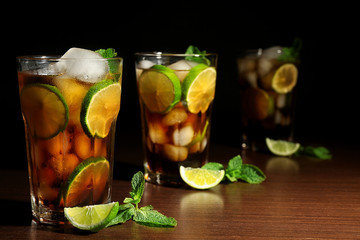 Cuba libre cocktails with lime and mint on wooden table