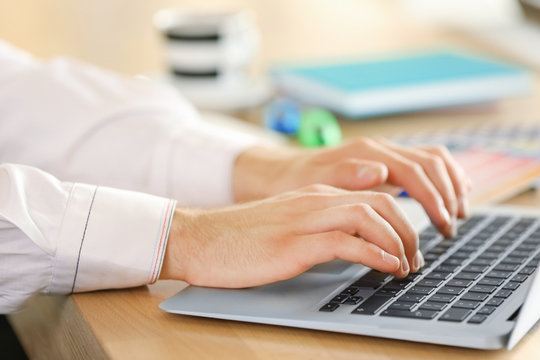 Man typing on laptop in office, closeup
