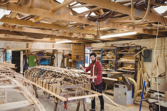 Carpenter preparing wooden boat frame in workshop