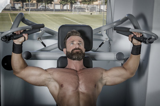 Entrenando en el gimnasio. Hombre con grandes músculos levantando peso mientras entrena en el gimnasio. Ponerse en forma.