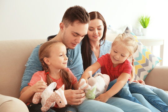 Happy parents with daughters playing toys on couch