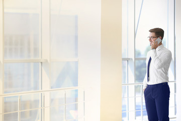 Fototapeta premium Handsome young lawyer talking on phone at office building