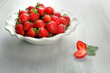 Plate with juicy strawberries on white wooden background