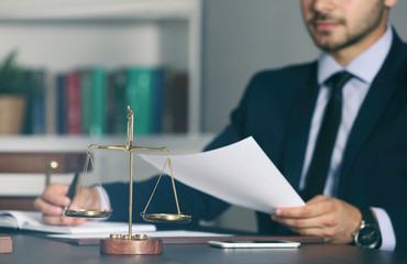 Naklejka premium Scales of justice and businessman sitting at table