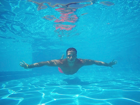 Sporty young man swimming underwater in pool