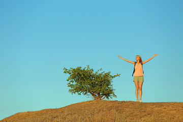 Young woman on hill on blue sky background