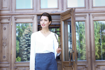 Beautiful businesswoman with clipboard out of office