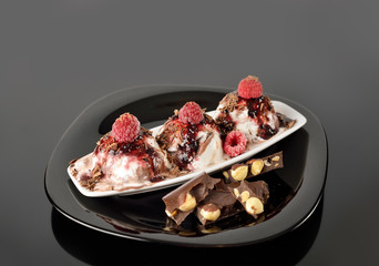 Food background. Scoops of ice cream with raspberries and jam on black.