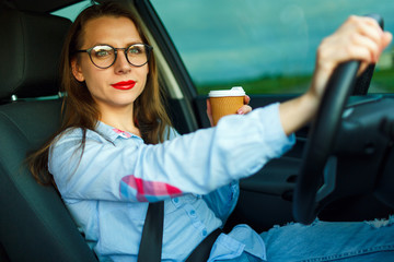 Woman with coffee to go driving her car