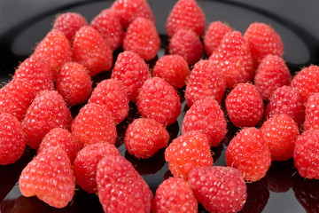 Fresh organic fruit - ripe red raspberry on black background selective focus