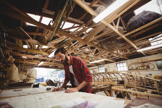 Carpenter looking at blueprint in workshop