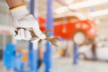 Car mechanic holding wrench at the car repair garage