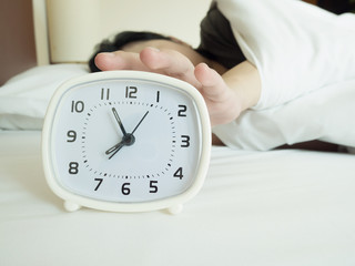 white alarm clock and sleeping woman