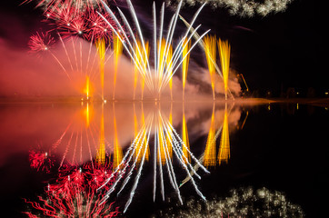 Fireworks display at night with reflections on water