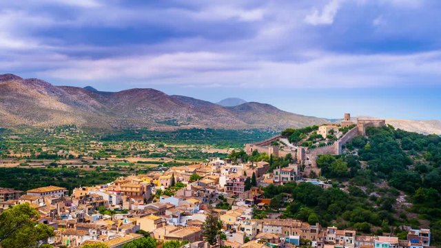 Capdepera castle on green hill in Mallorca island, Spain. Beautiful landsacape with medieval architecture, green trees and blue sky with clouds.