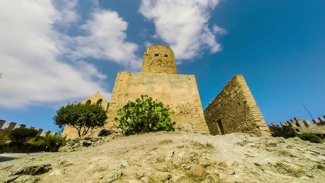 Capdepera castle tower in Mallorca island, Spain. Beautiful medieval architecture, green trees and blue sky with clouds.