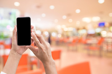 Woman's and holding smart phone with blur restaurant background