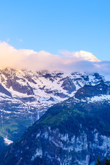 View of beautiful Alps with snow-capped mountain tops and nice clouds at sunset.
