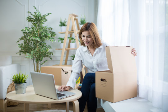 home, post, delivery and happiness concept - smiling young woman opening cardboard box at home