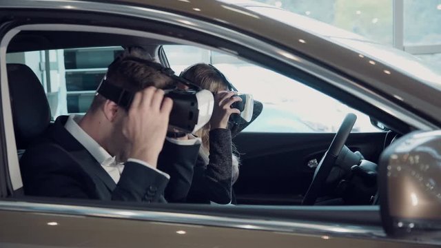 Young woman going for a test drive with the salesman in a new car as she makes a selection for her purchase, or she to pass virtual exam for driver license using virtual reality glasses.