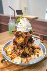 Waffle chocolate ice cream with various fruit and whip cream on zinc tray