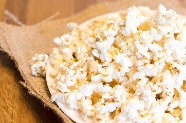 A selected focus of a popcorn on white plate and wooden table