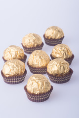 Chocolate ball in a gold foil paper on a background.