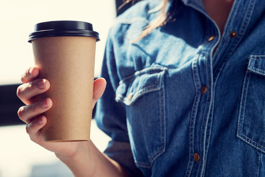 Young woman drinking coffee from disposable brown paper cup 